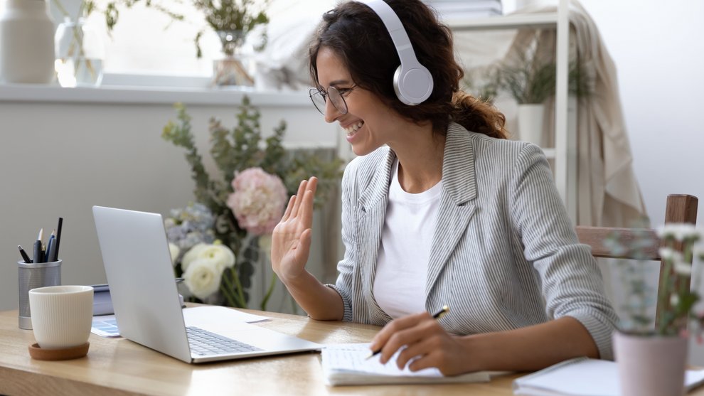 Eine Frau sitzt vor ihrem Laptop und nimmt an einer Onlinekonferenz teil