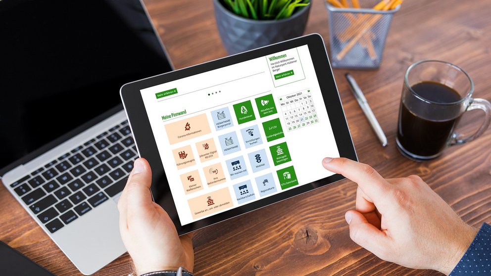 Jemand hält ein Tablet in Händen und benutzt das Bürgerportal Amt Hüttener Berge.