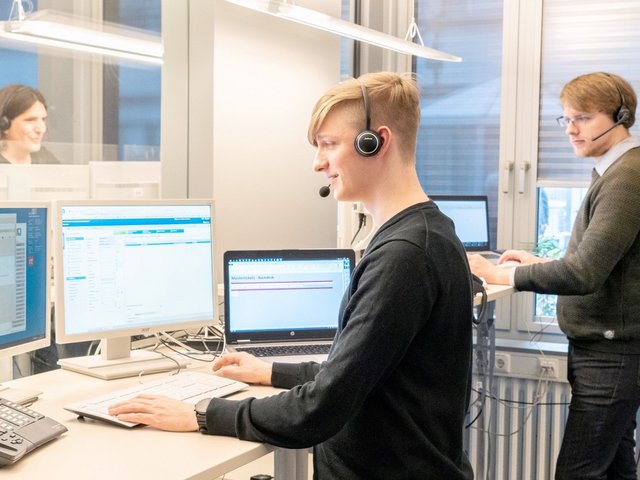 Mehrere Service-Mitarbeiter arbeiten an Computern und führen über Headsets Kundengespräche.