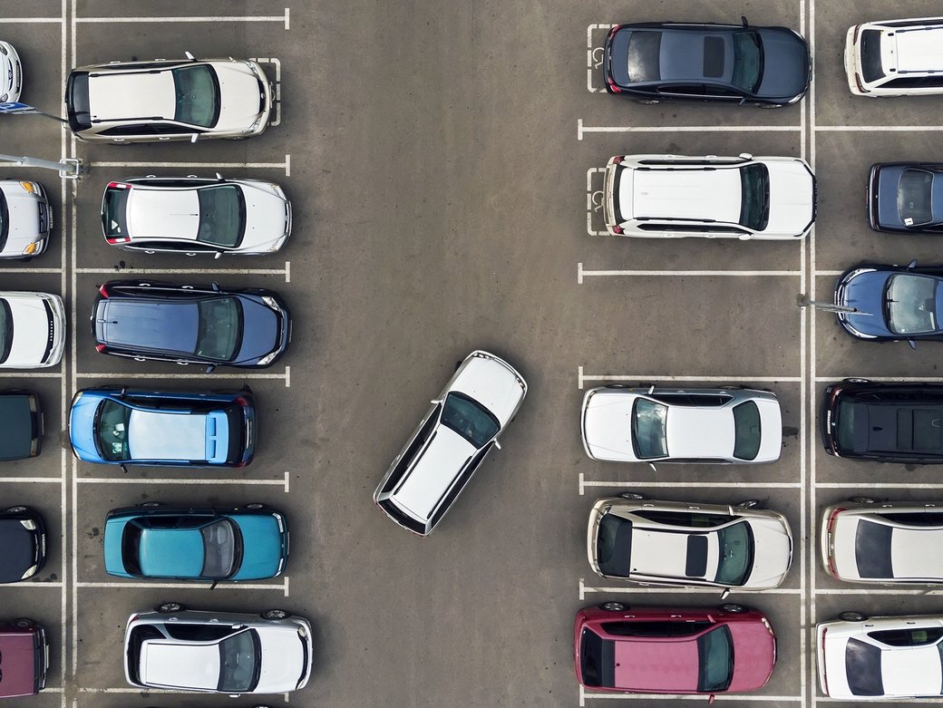 Ein Parkplatz mit vielen parkenden Autos aus der Vogelperspektive. Nur eine Parklücke ist frei.
